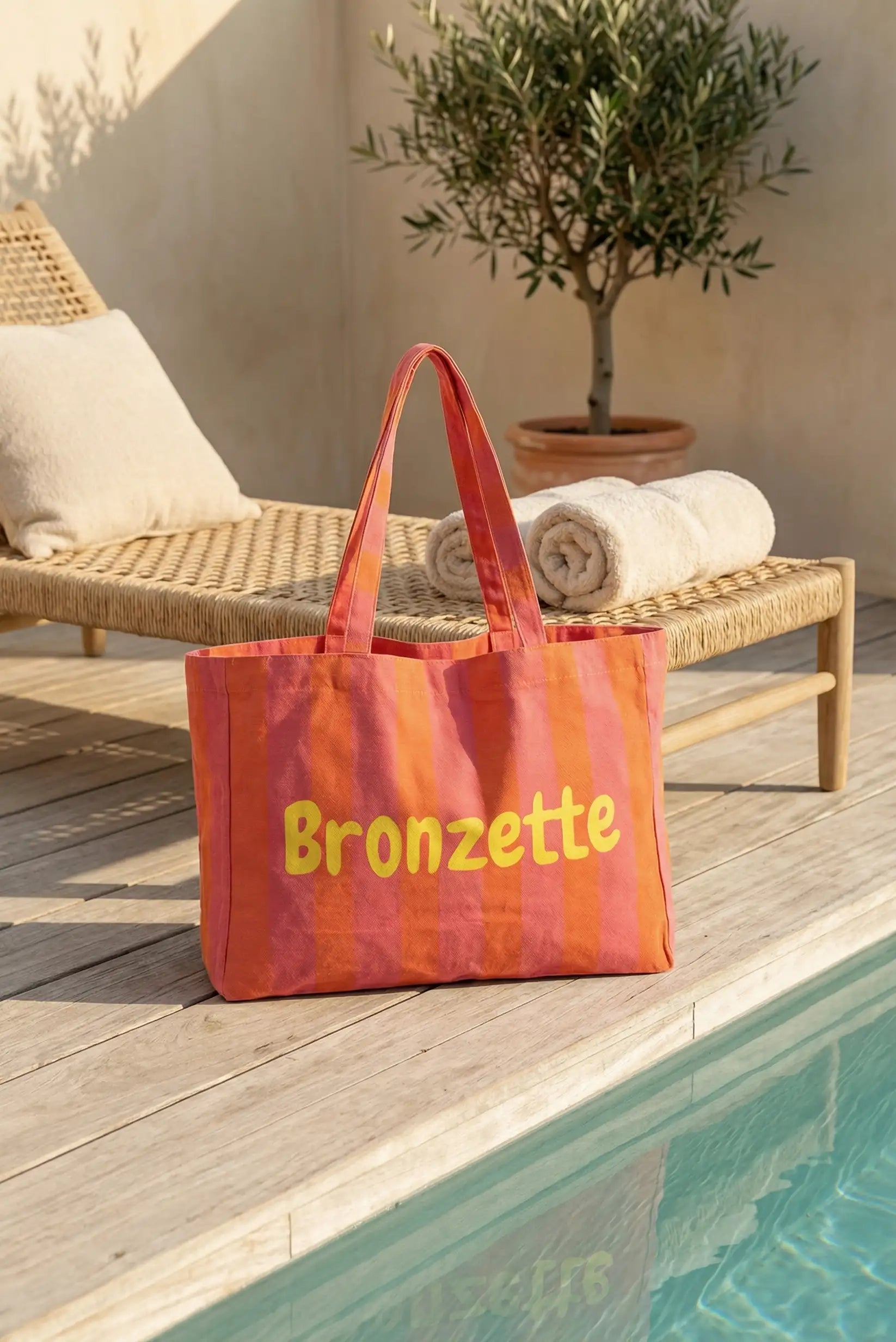 Bolsa de tela rayas rojas y naranjas junto a piscina, ideal para playa o verano
