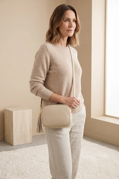 Mujer con bolso bandolera beige con decoración de piel y borla, look casual elegante