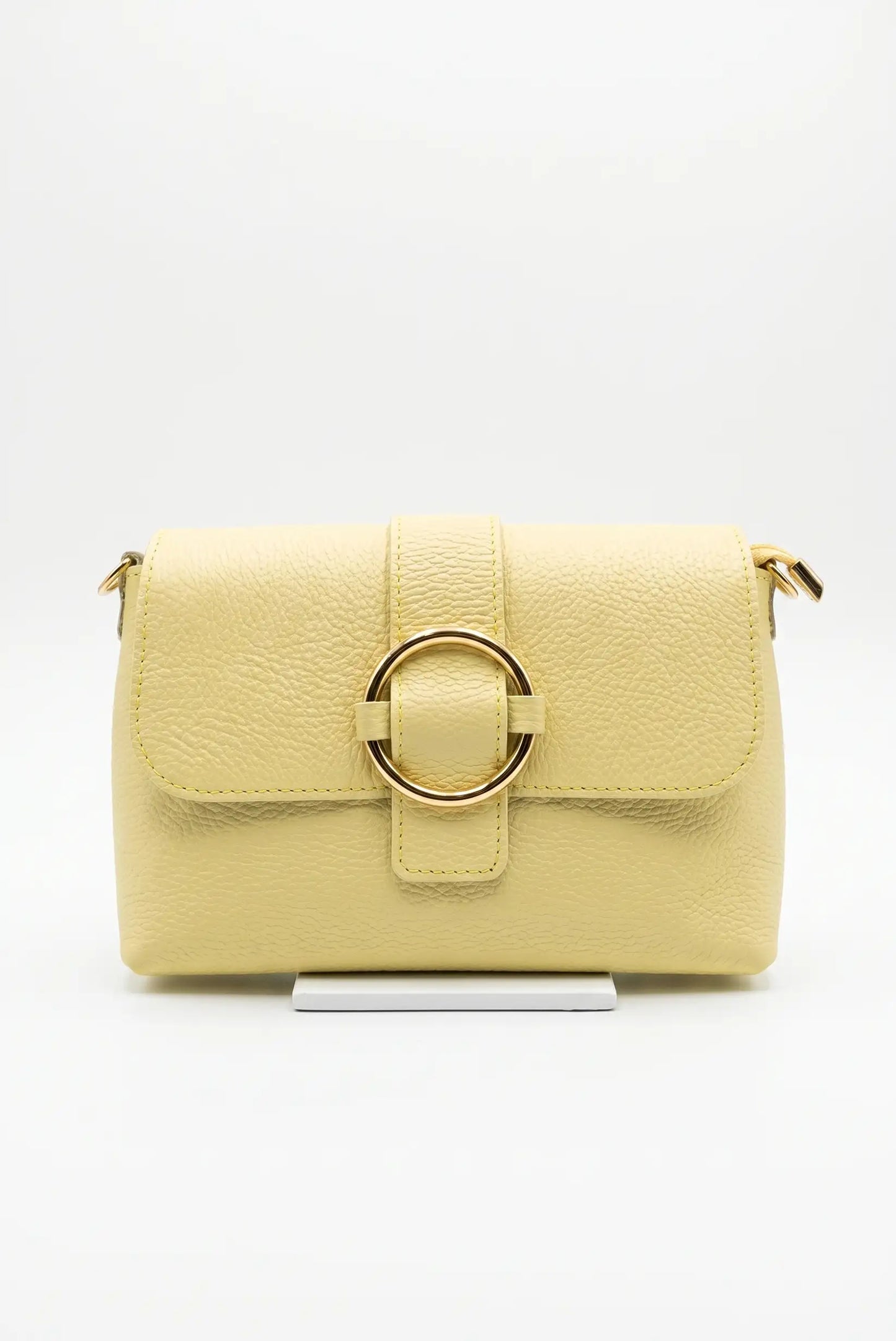 Bolso bandolera pequeño para mujer en color amarillo, con textura y hebilla dorada frontal.