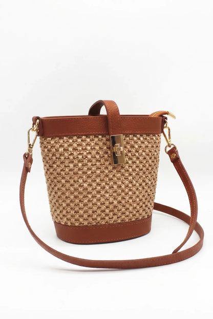 Bolso bandolera de rafia beige con detalles de piel marrón y cierre dorado elegante.