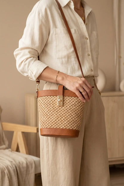 Bolso bandolera de rafia y piel marrón, estilo casual, con cierre metálico dorado.