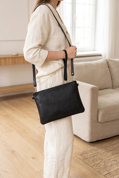 Mujer con conjunto beige llevando un bolso clutch de piel negro de CHICA del Sur