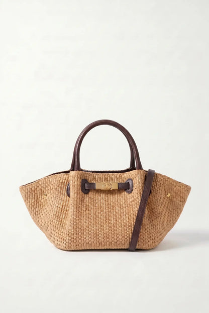 Bolso de paja tejida con asas de cuero marrón y cierre metálico dorado, ideal para verano y playa