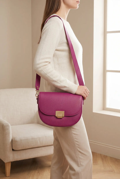 Mujer con bolso bandolera de piel en color fucsia y cierre dorado