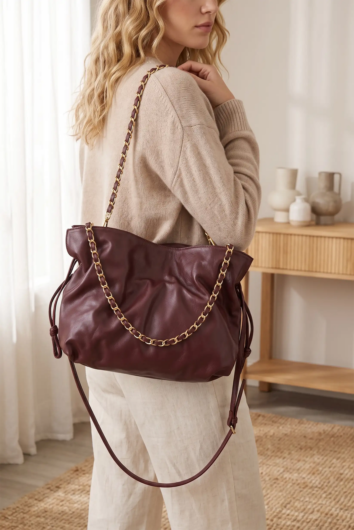 Mujer con bolso shopper de piel color burdeos con asa de cadena dorada