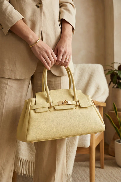 Bolso de mano amarillo pastel de piel para mujer, elegante y moderno, en ambiente cálido