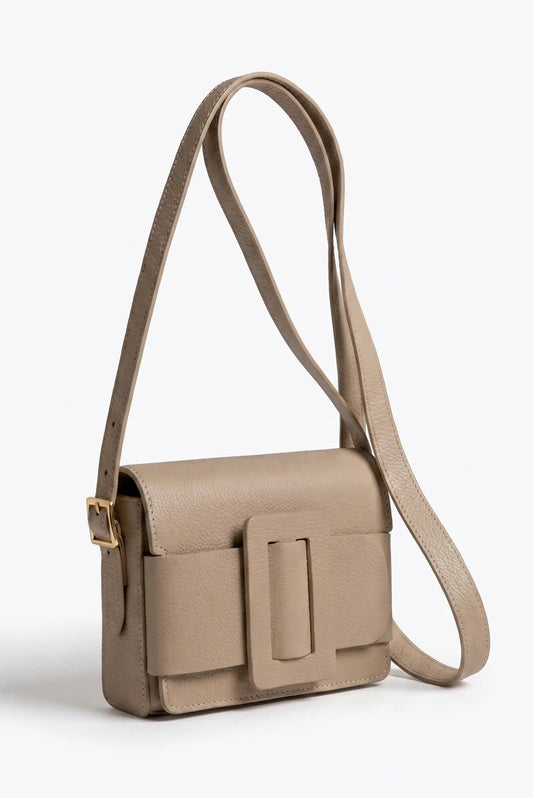 Bolso bandolera taupe de piel sintética con detalle de hebilla rectangular y correa ajustable.