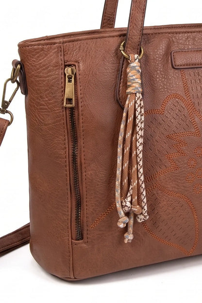 Bolso de mano en cuero marrón con detalle de borla y relieve floral