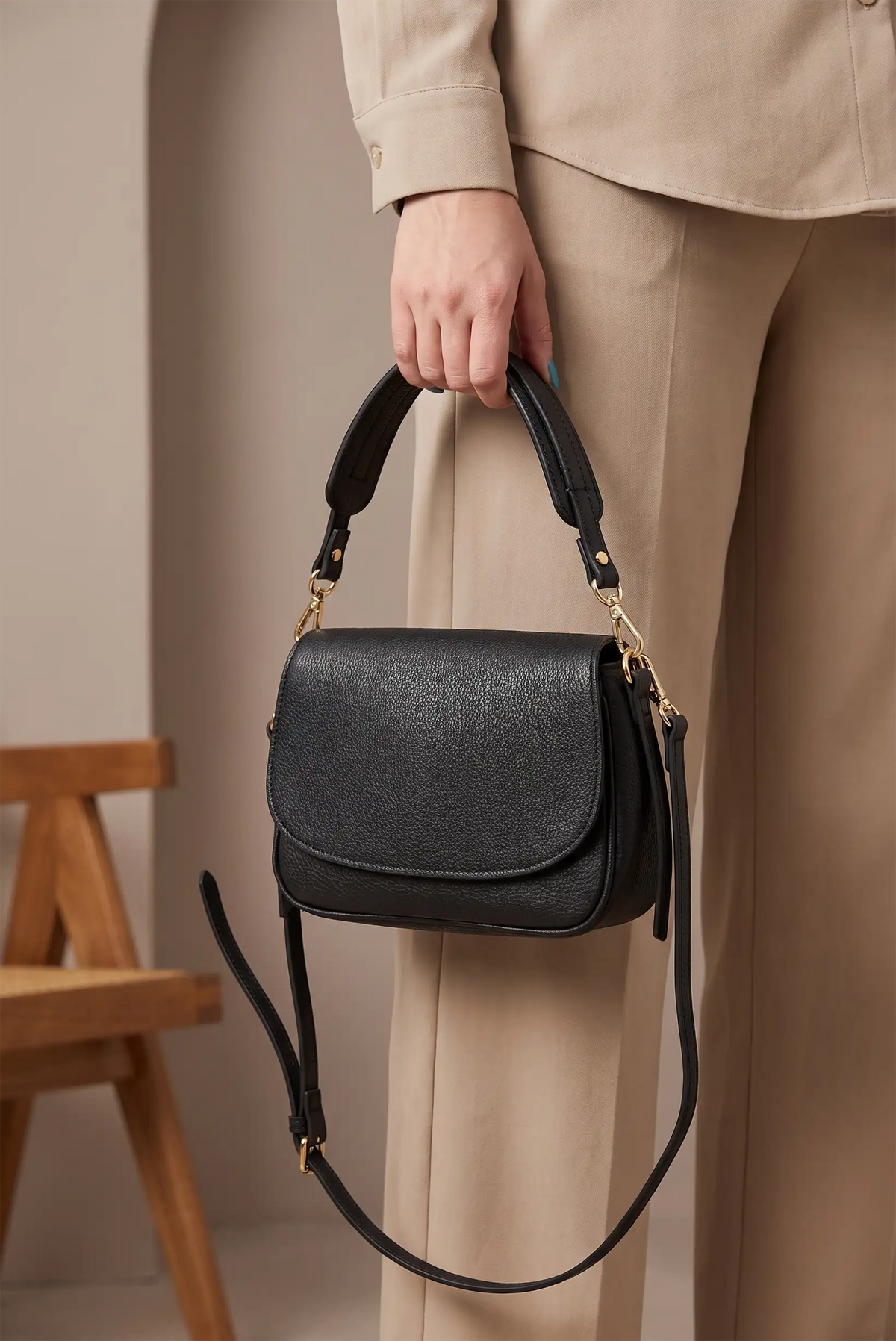 Bolso de mano negro de piel granulada con correa ajustable y detalles dorados