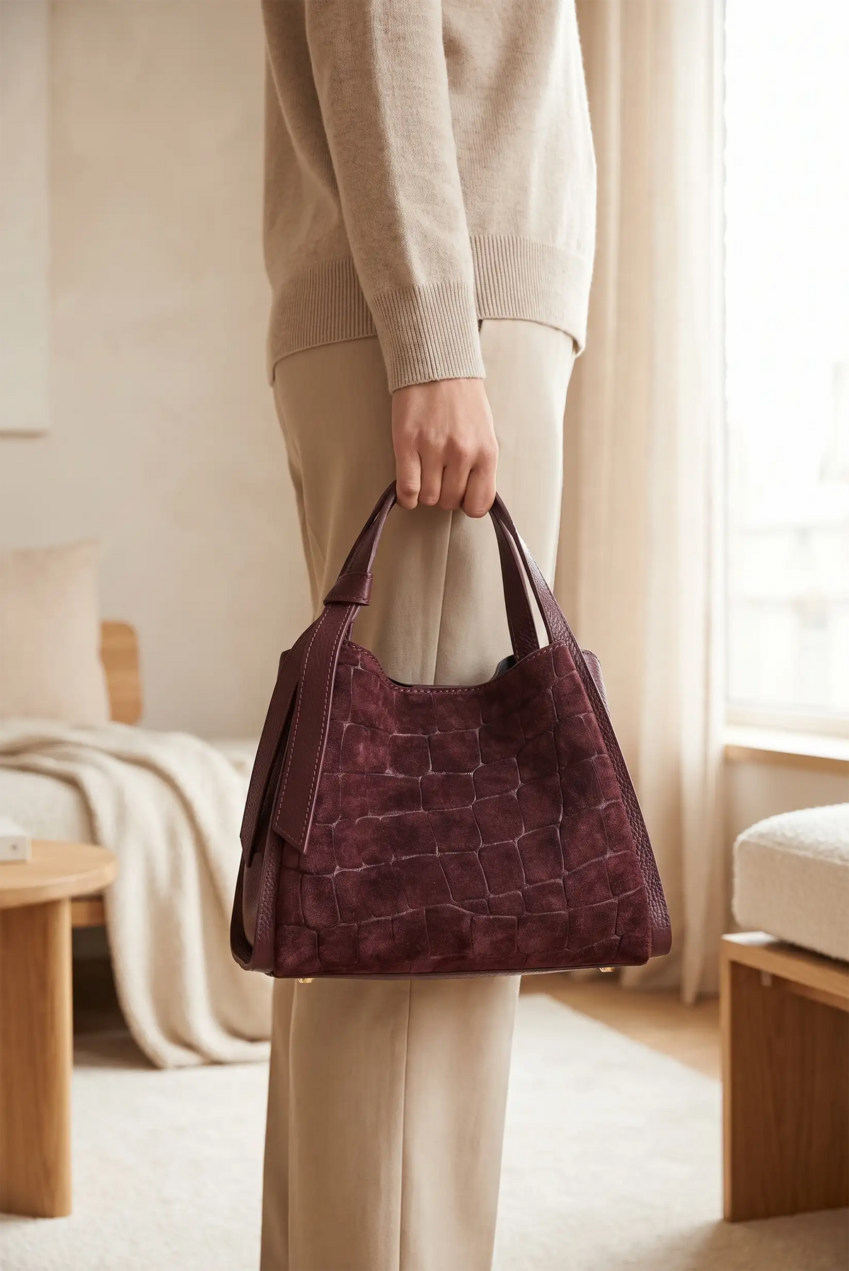 Bolso de mano en ante efecto cocodrilo burdeos de CHICA del Sur sostenido por una mujer.