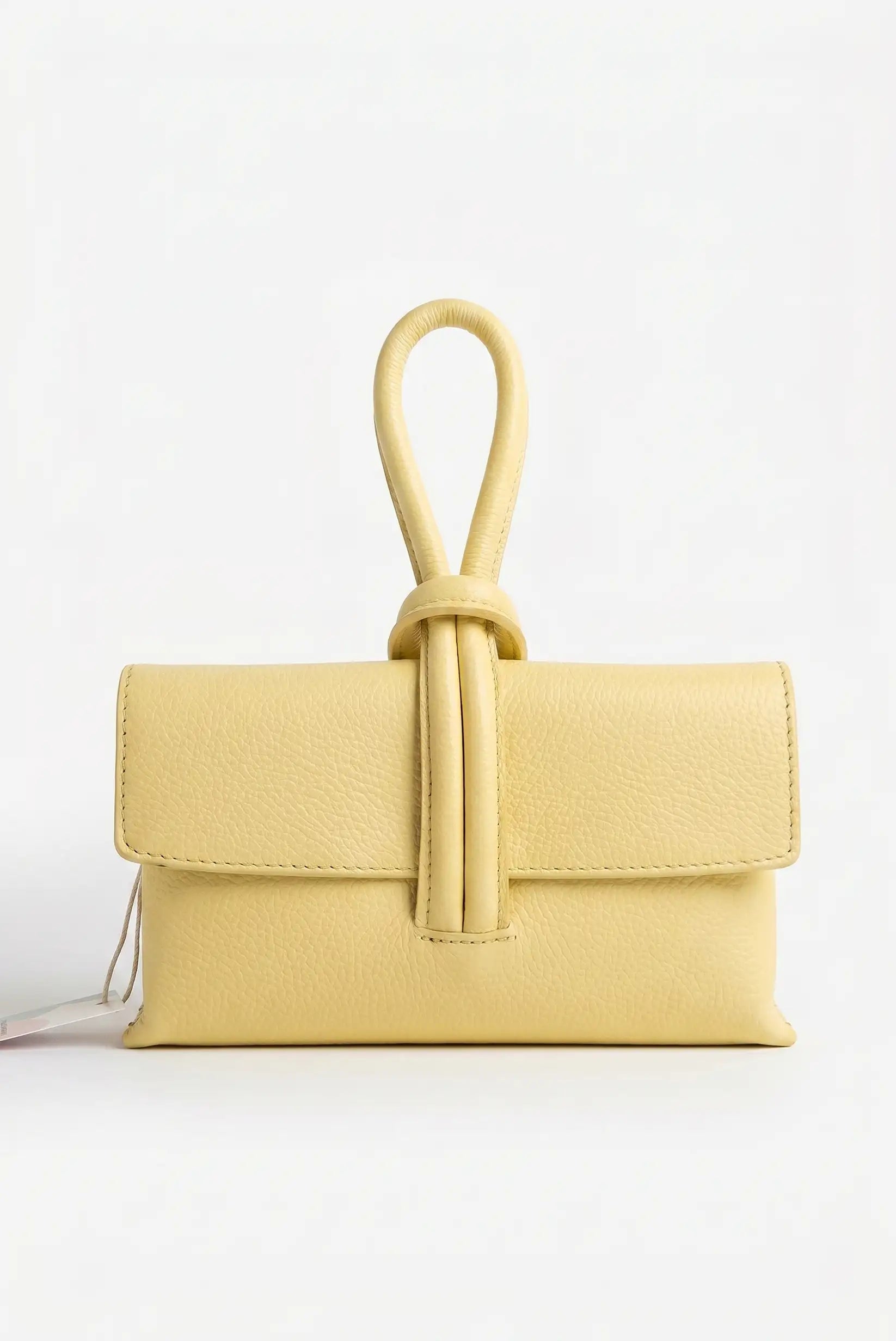 Bolso de mano pequeño de piel amarillo con cierre tipo nudo, estilo bandolera elegante.