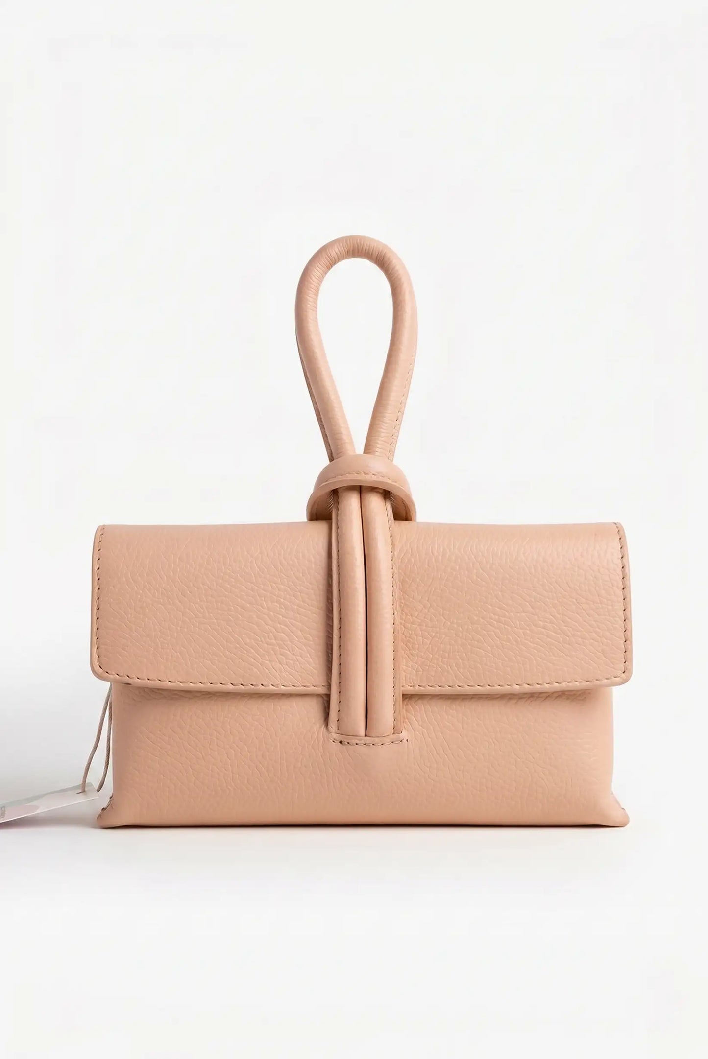 Bolso de mano pequeño nude de piel con asa tipo nudo, fondo blanco, estilo casual elegante
