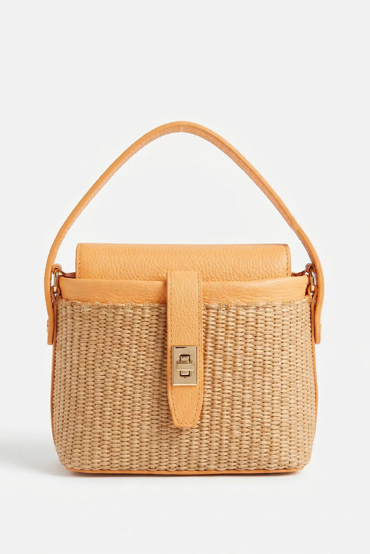 Bolso de mano pequeño de rafia y cuero salmón con asa corta y cierre metálico elegante.