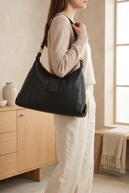 Mujer luciendo un bolso de hombro de piel negra de CHICA del Sur con pantalones blancos.