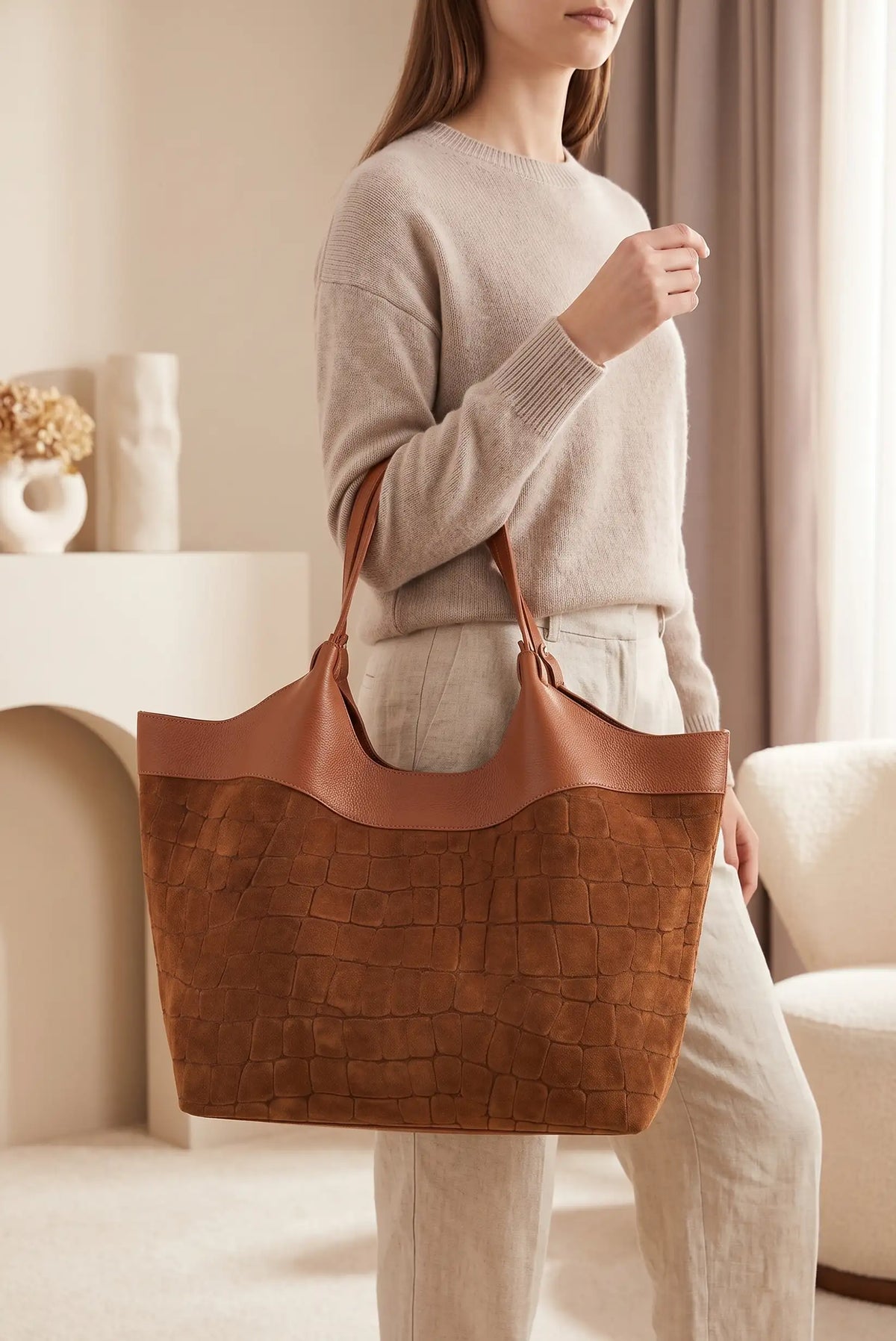 Mujer vistiendo jersey beige y pantalón blanco con bolso shopper grande de piel de vaca camel