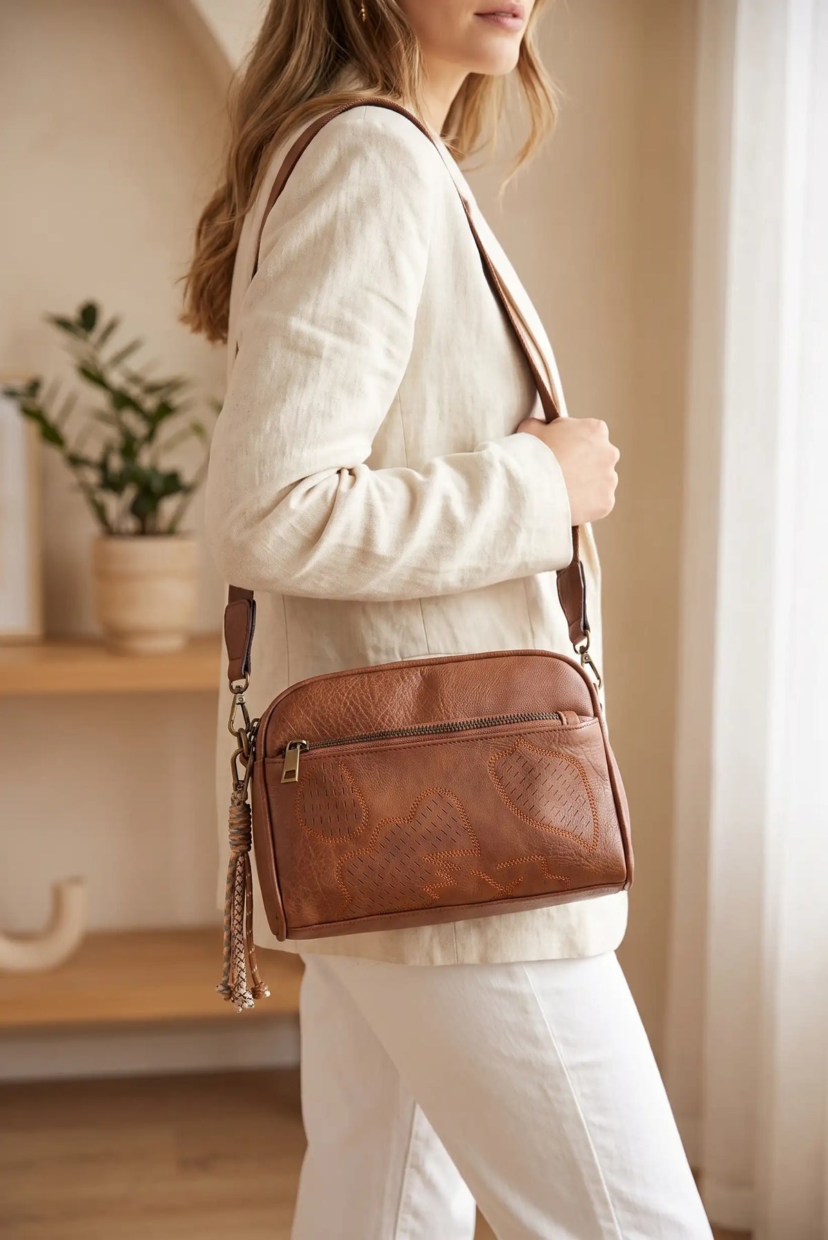 Mujer con blazer beige y bolso bandolera de cuero marrón con relieves