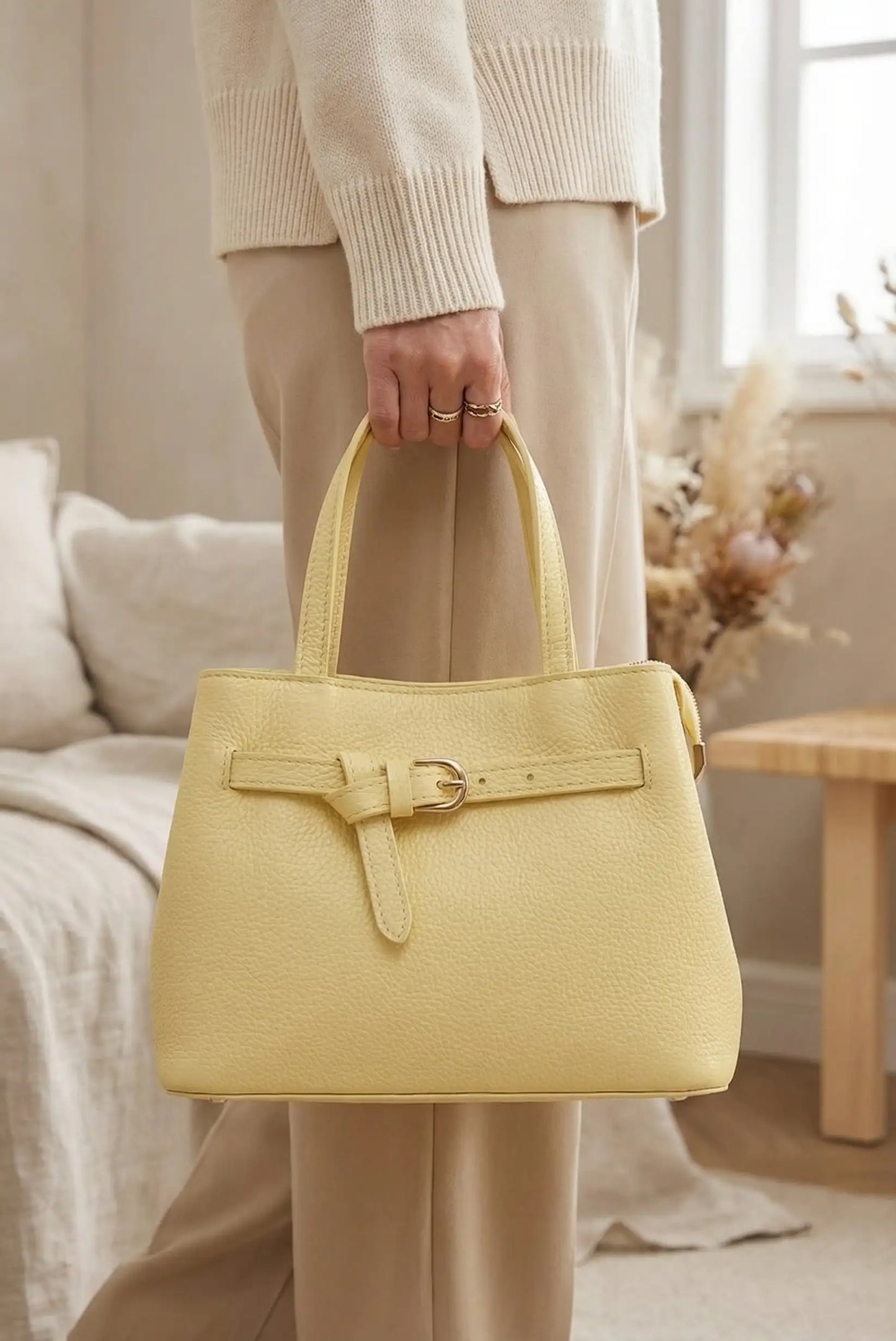 Bolso mediano amarillo pastel de mano y bandolera, estilo casual para mujer, en interior elegante.