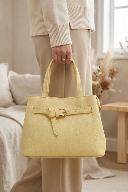 Bolso mediano amarillo pastel de mano y bandolera, estilo casual para mujer, en interior elegante.