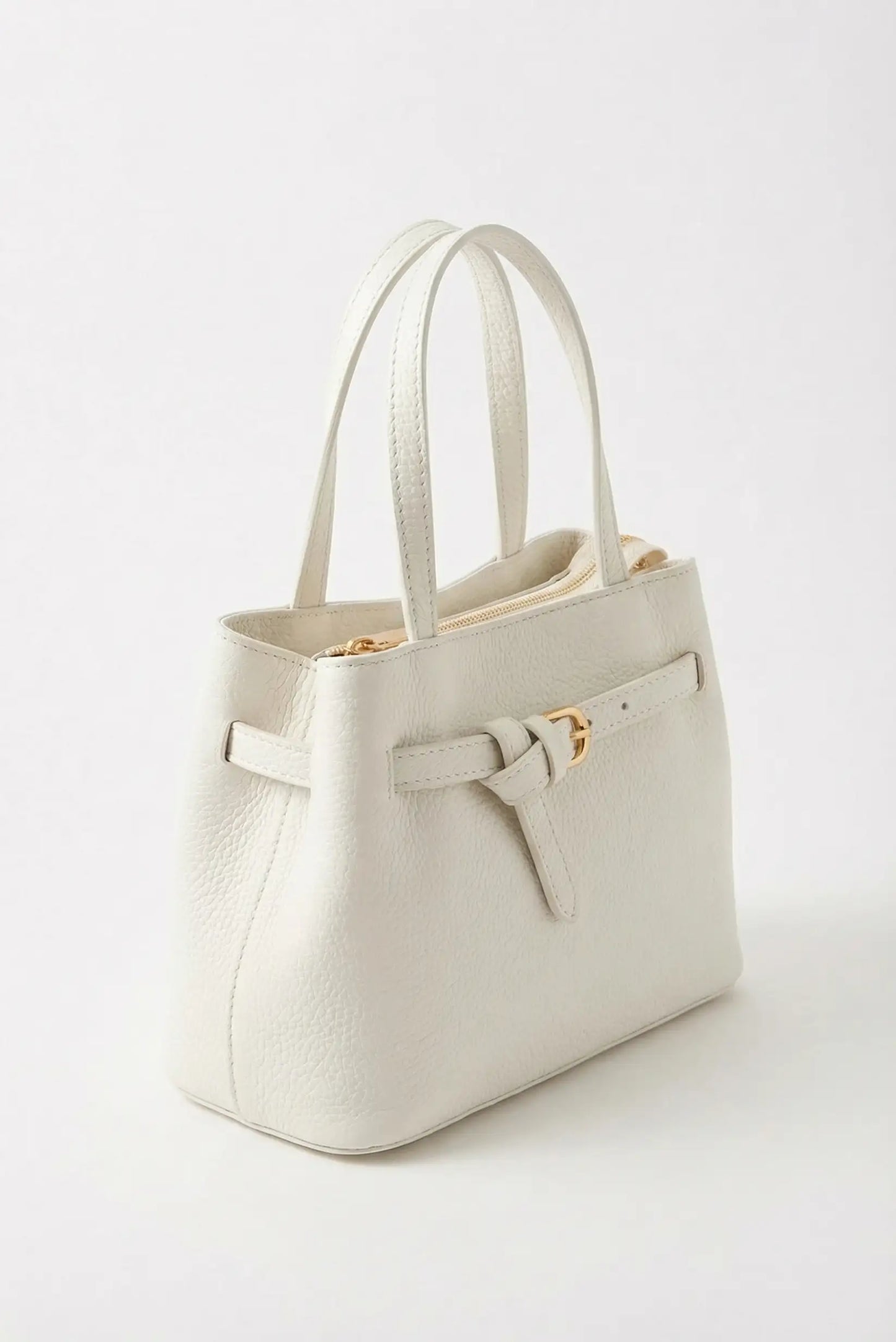 Bolso mediano blanco de mano y bandolera con textura y detalles dorados, estilo primavera.