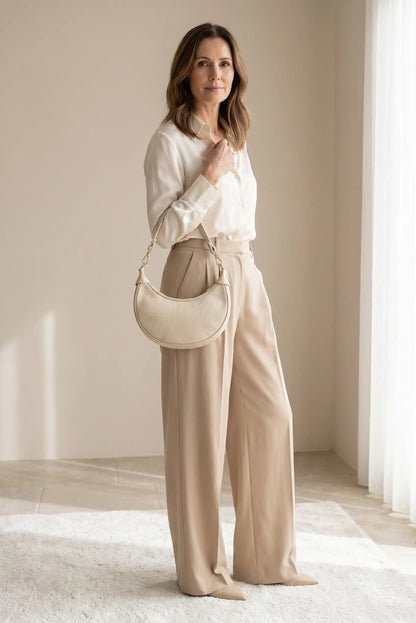 Mujer con bolso mediano de piel beige estilo gondola y portagafas, look elegante y casual