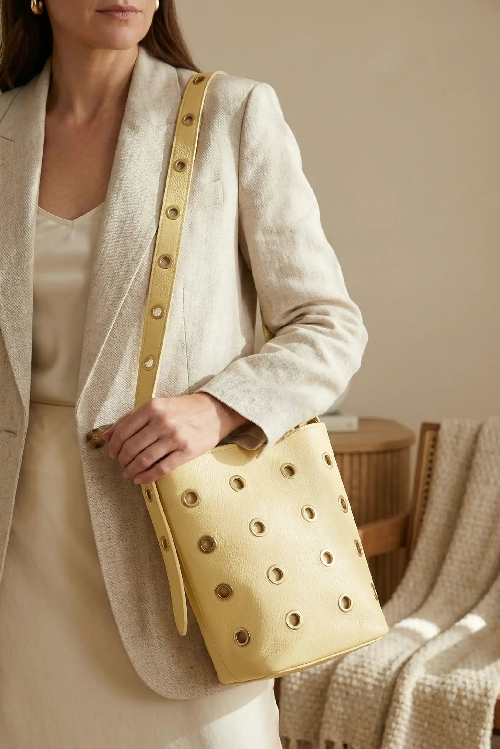 Bolso mediano amarillo pastel de piel con tachuelas metálicas, estilo casual femenino.