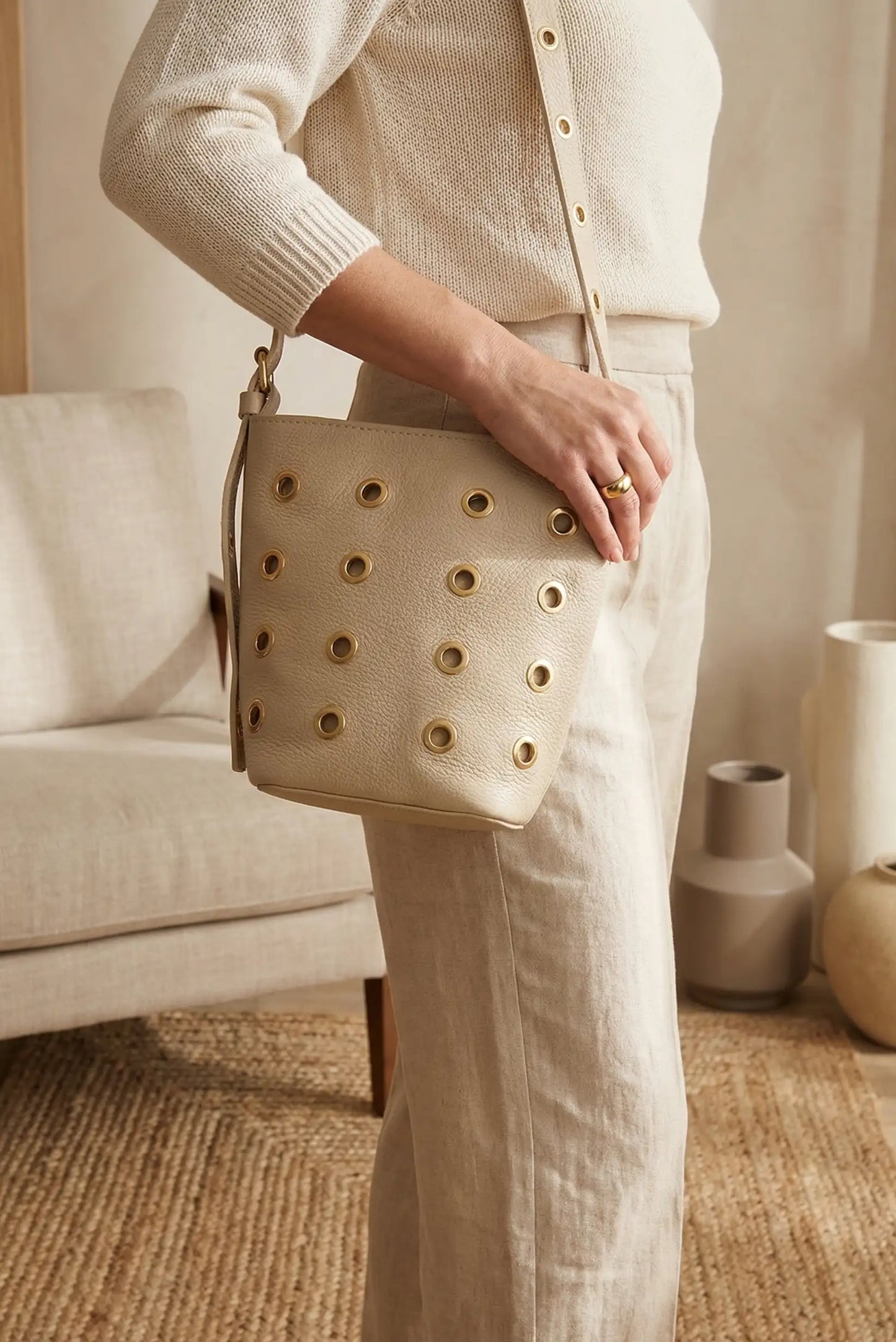 Bolso mediano de piel beige con tachuelas doradas, look casual femenino elegante