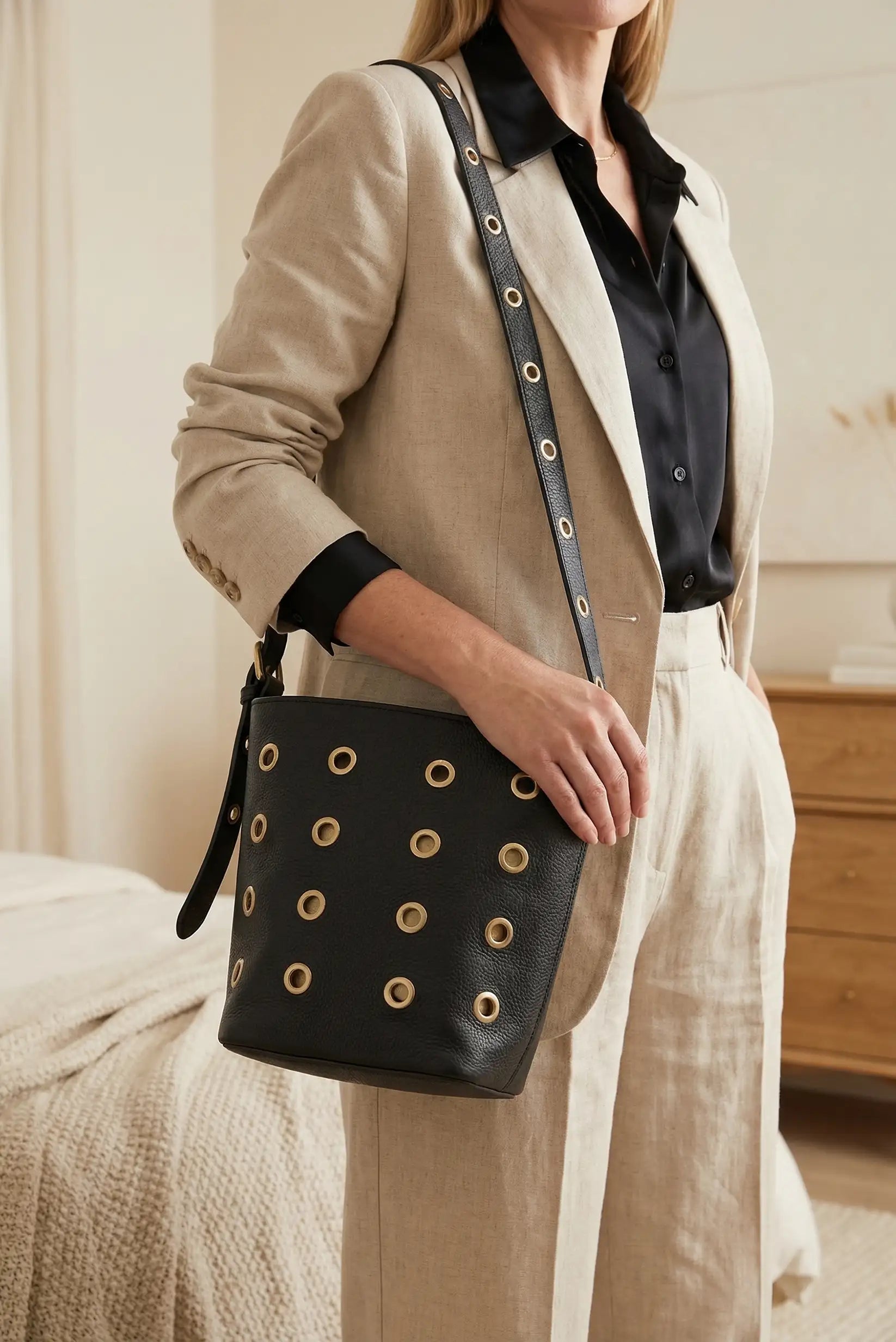 Bolso mediano negro de piel con tachuelas doradas, correa ajustable, estilo casual femenino.