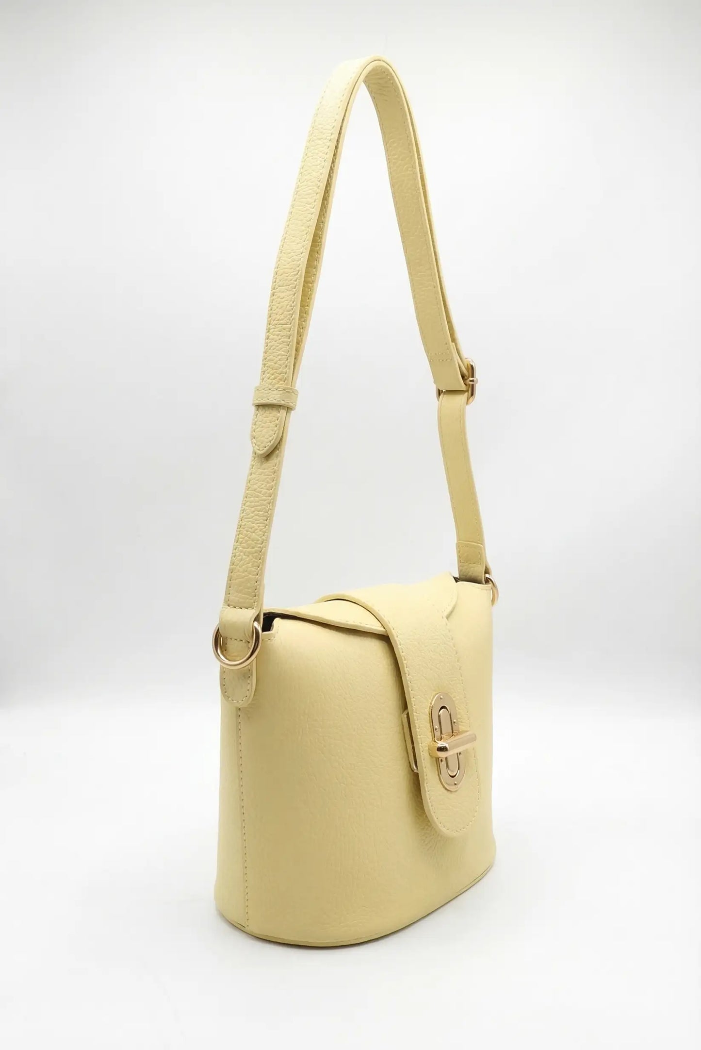 Bolso bandolera mediano de mujer en color amarillo pastel, con cierre metálico y correa ajustable.