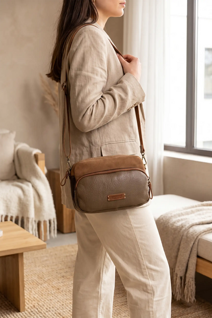Mujer con blazer beige y bolso bandolera de cuero marrón en tono topo.