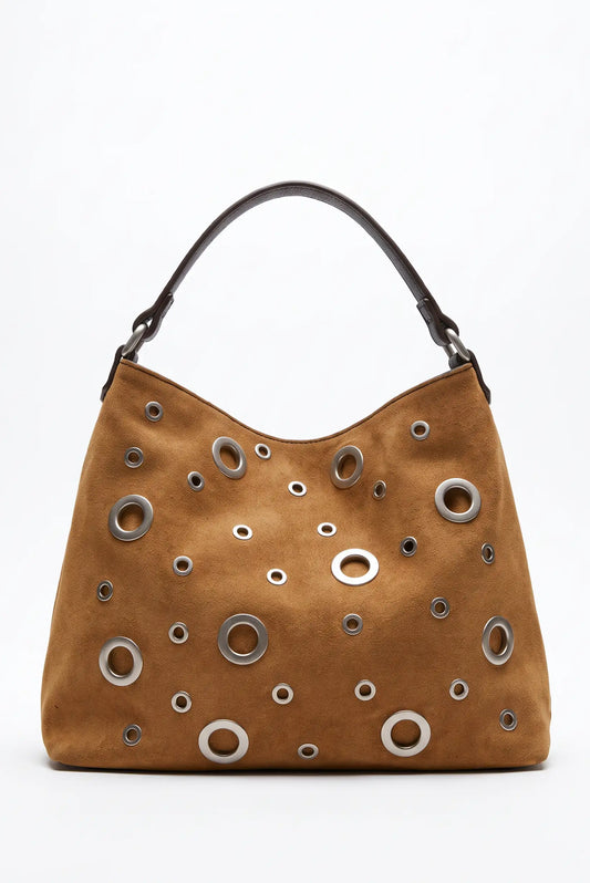 Bolso de mujer camel de CHICA del Sur con detalles metálicos circulares y asa marrón.