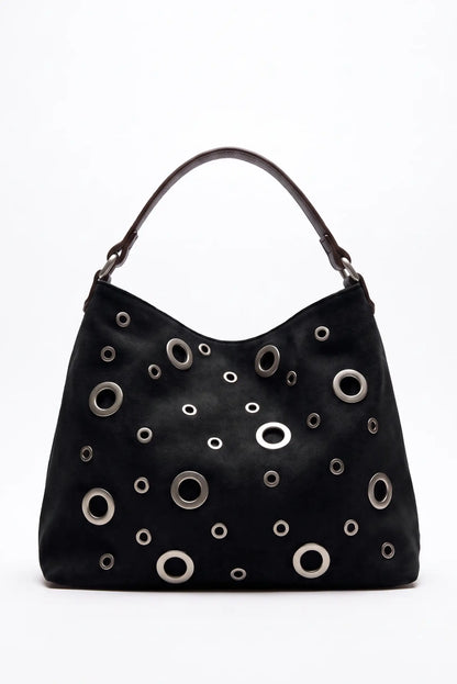 Bolso negro de mujer CHICA del Sur con detalles metálicos circulares y asa marrón.