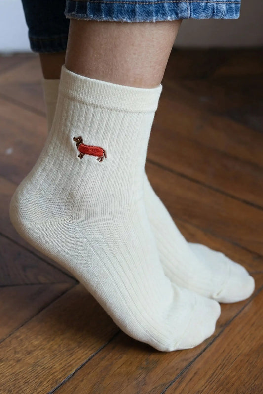 Calcetines crudos de mujer con bordado de perro salchicha, estilo casual, sobre suelo de madera.