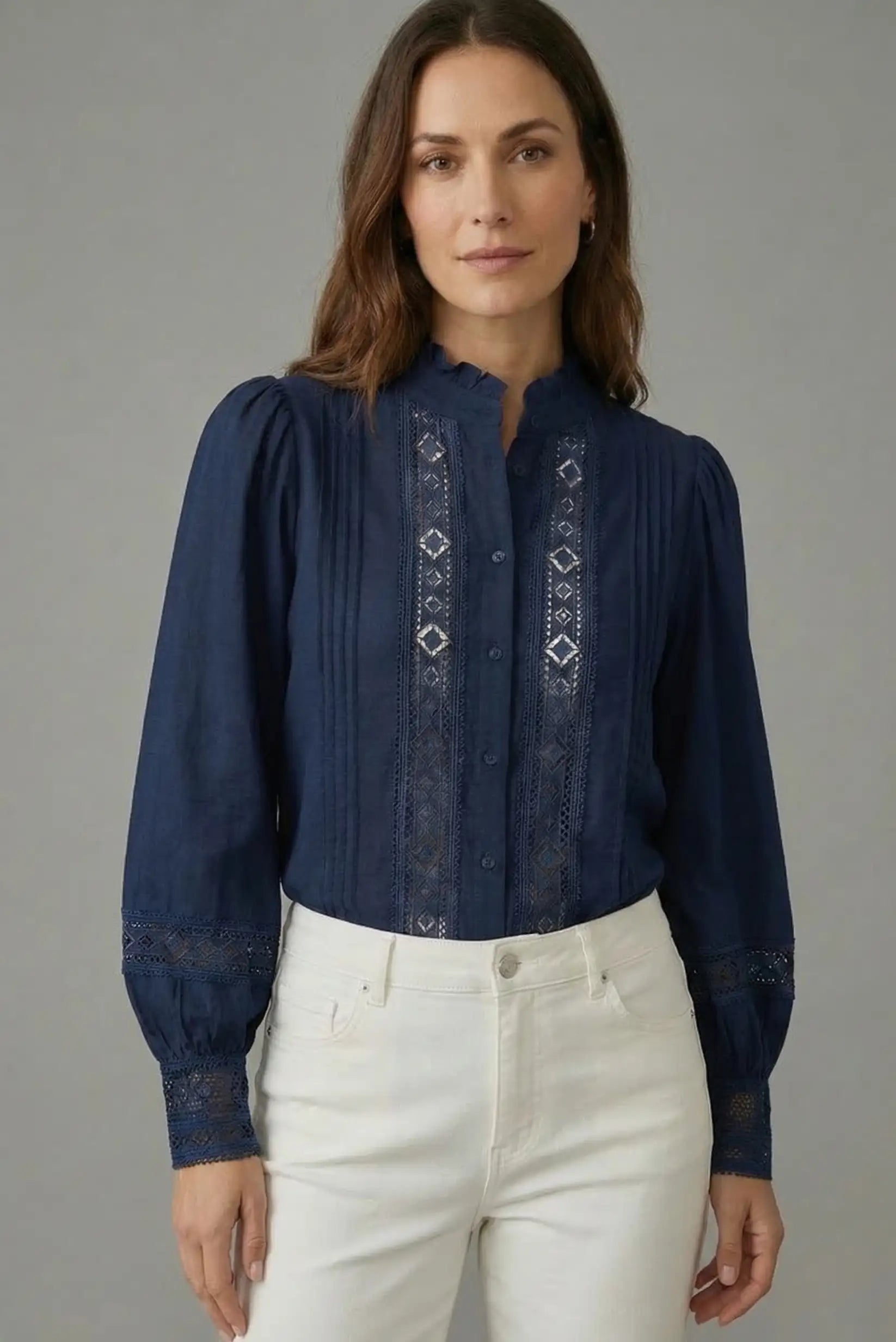 Mujer con camisa azul de manga larga, bordados frontales y pantalón blanco, moda femenina casual.