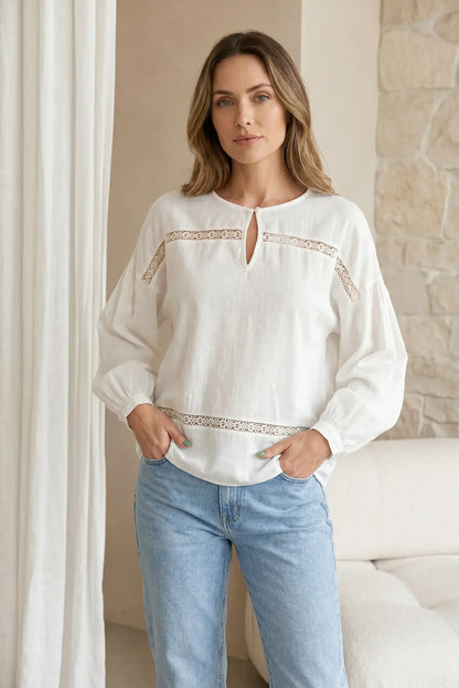 Camisa blanca de manga larga con bordados y jeans, look femenino casual.