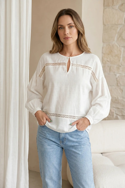Camisa blanca de manga larga con bordados y jeans, look femenino casual.