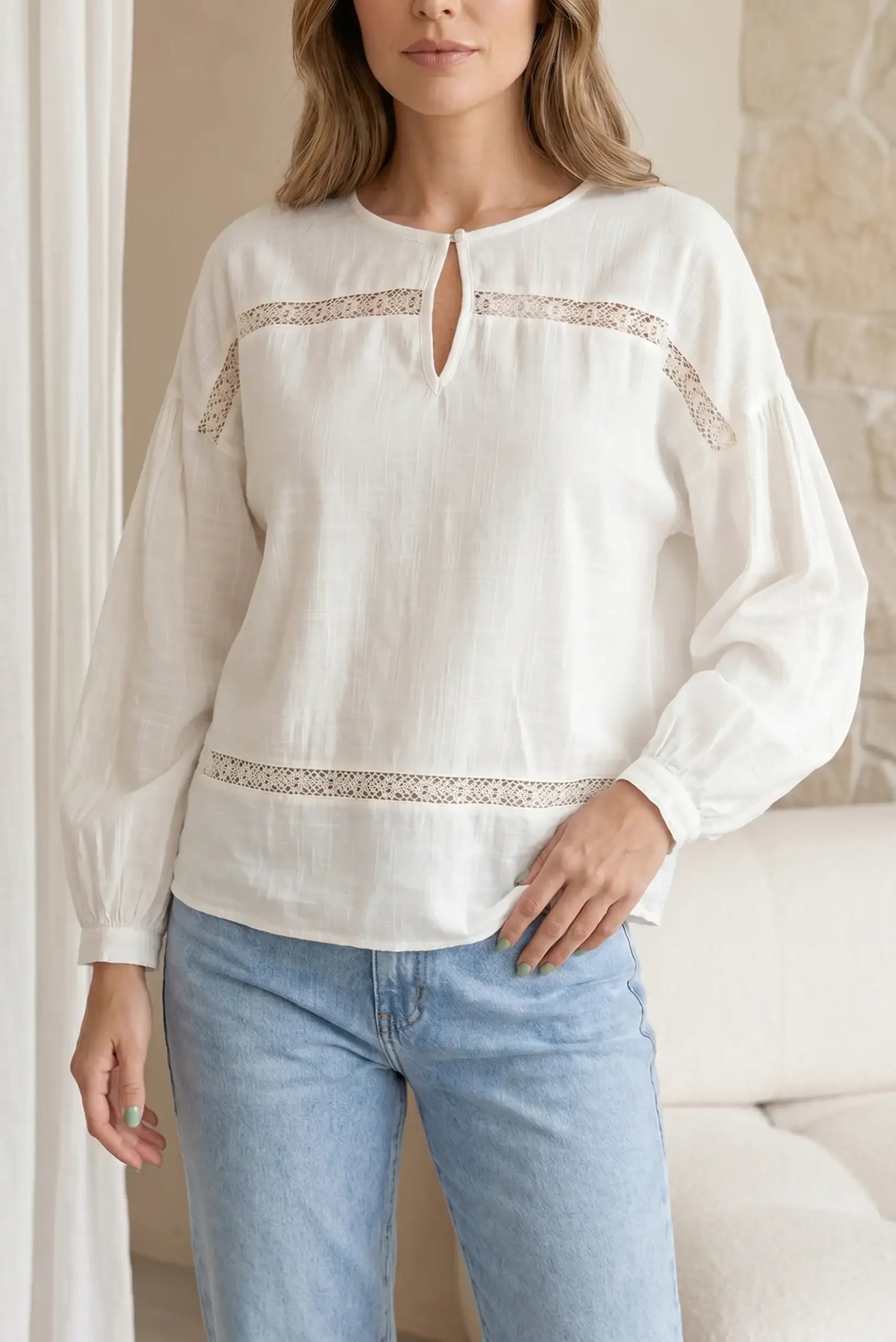 Camisa blanca de manga larga con detalles de encaje, estilo casual femenino.