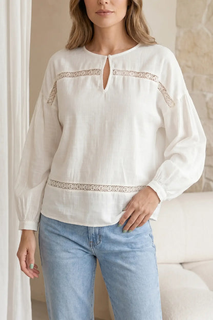 Camisa blanca de manga larga con detalles de encaje, estilo casual femenino.