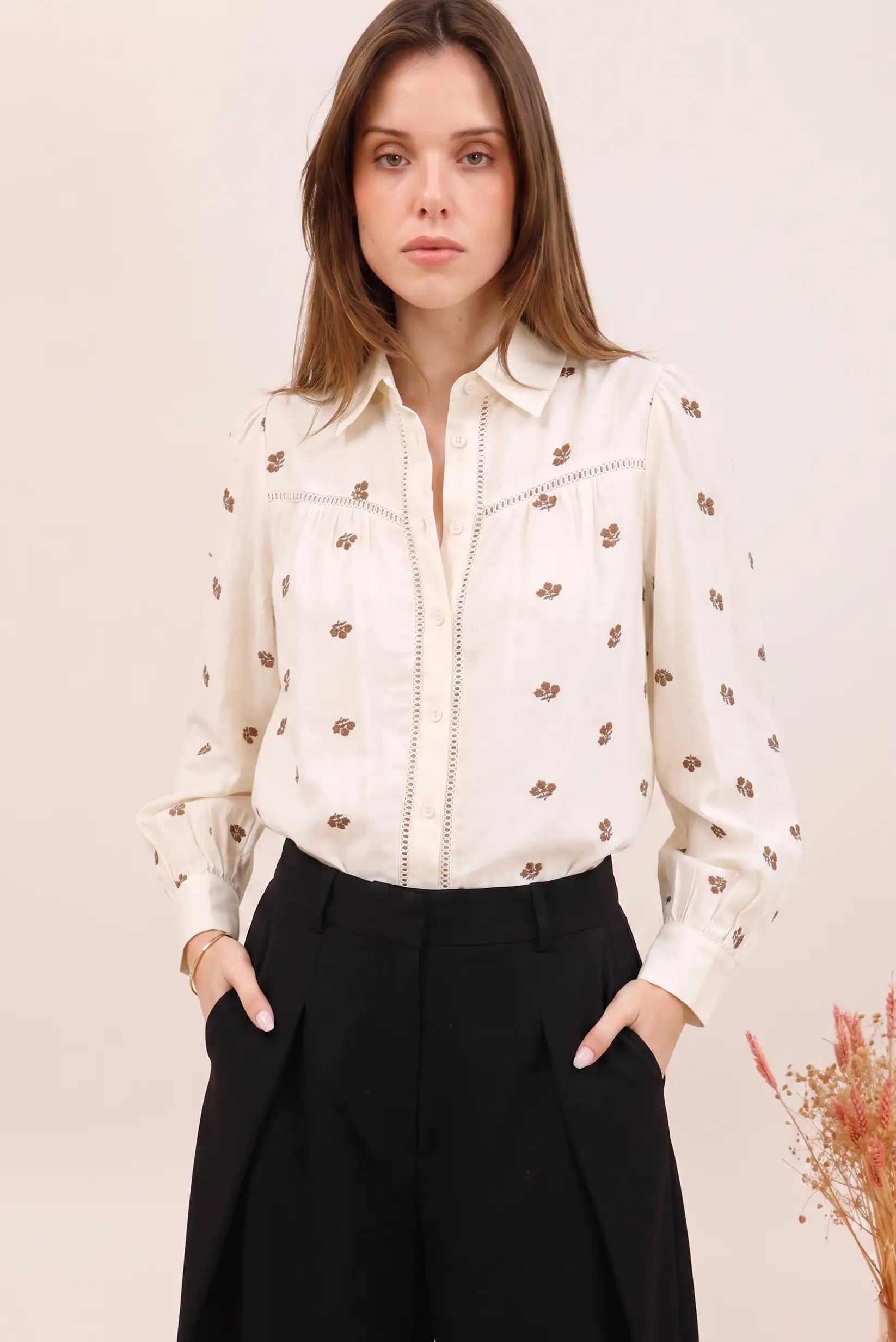 Blusa blanca con estampado floral marrón, manga larga y detalles bordados, ideal para look femenino y elegante