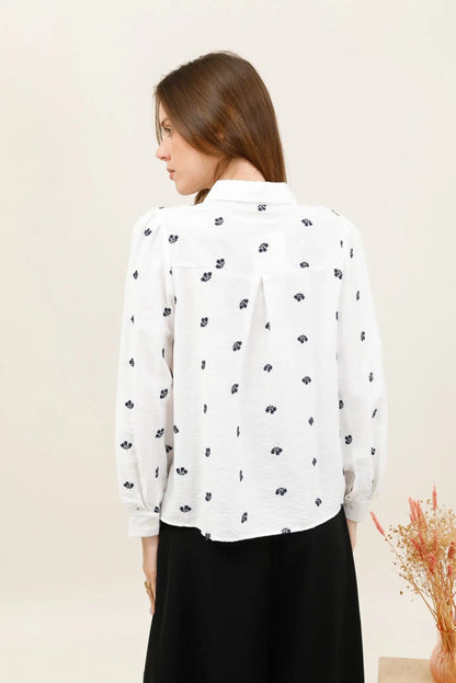 Vista trasera de mujer con camisa blanca de manga larga y estampado floral azul marino