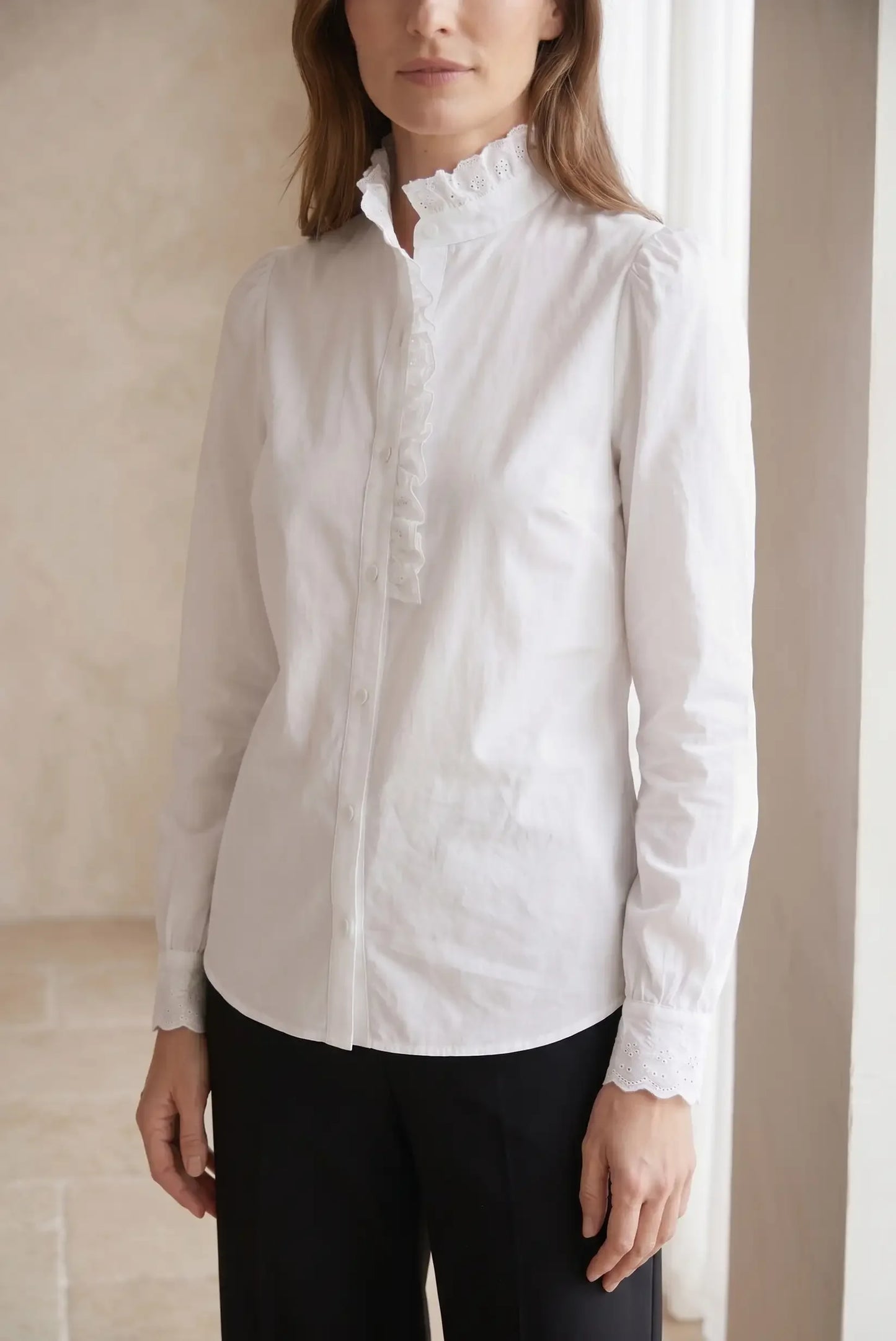 Camisa blanca de mujer de manga larga con volantes y cuello alto, look casual elegante.
