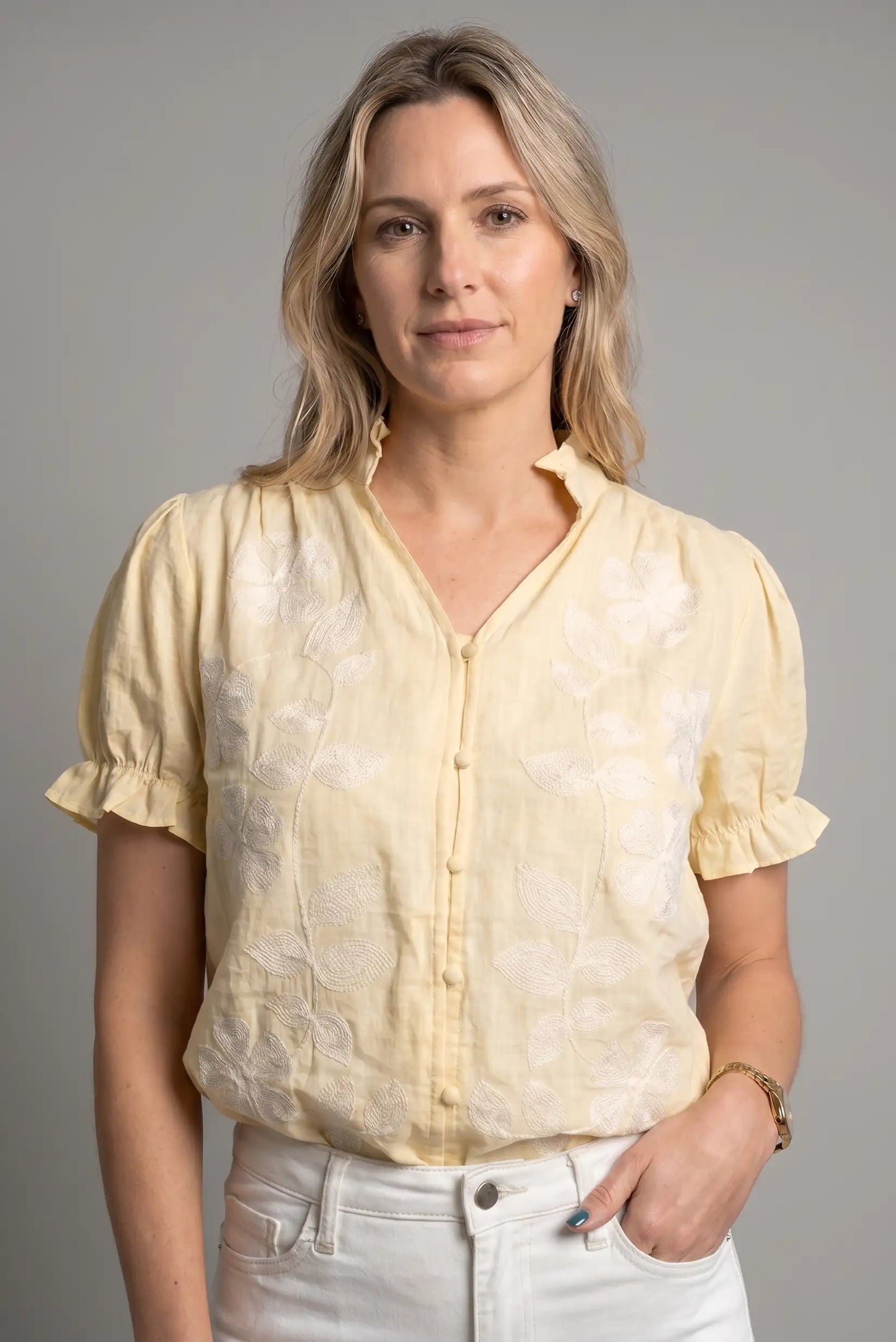Mujer con camisa amarilla de manga corta y bordados florales, look casual de primavera.