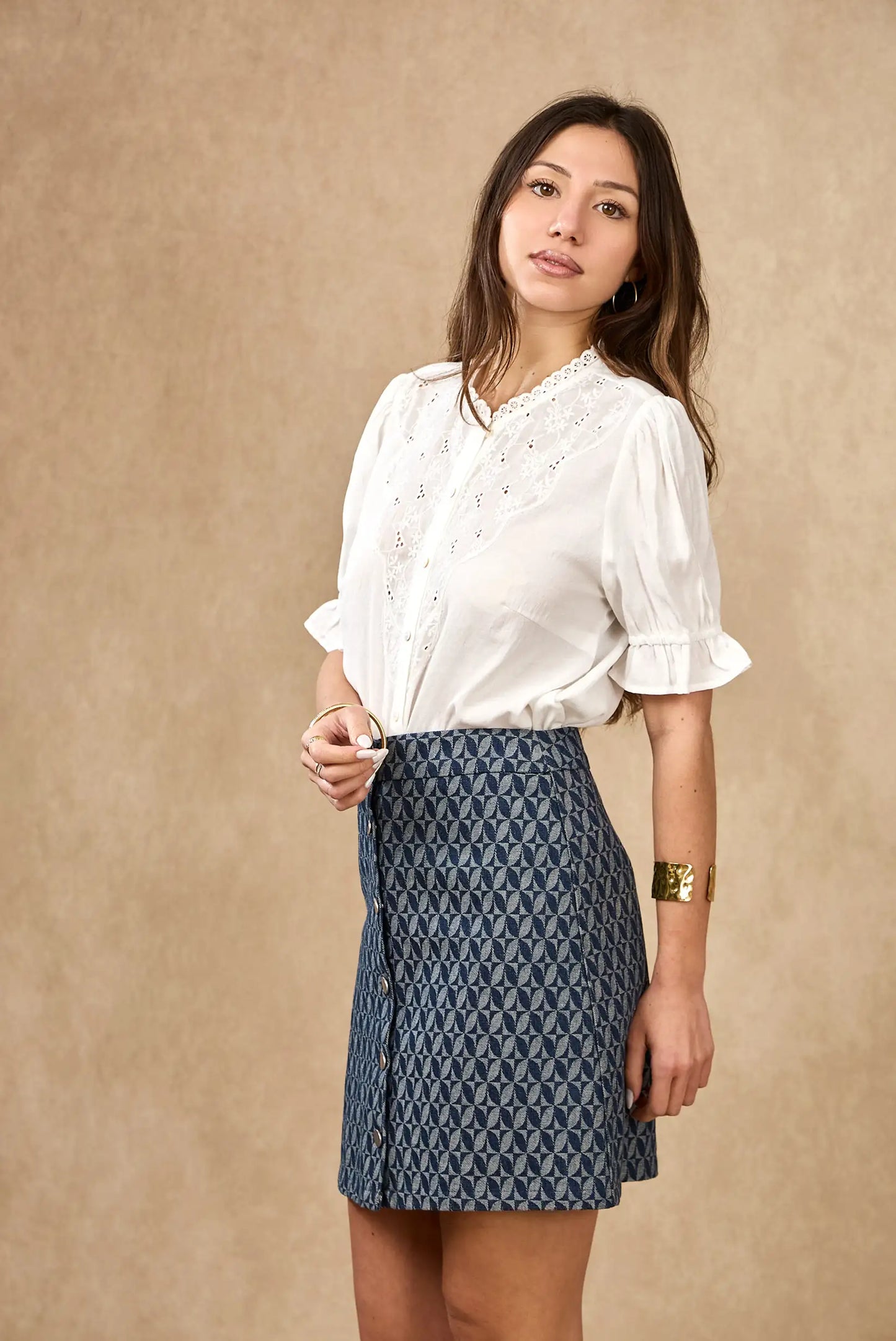 Mujer con camisa blanca bordada de manga corta y falda azul estampada, moda femenina casual.
