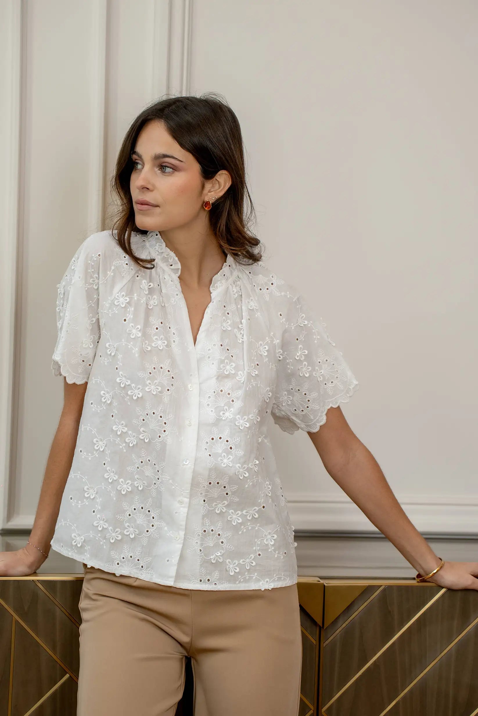 Mujer con camisa blanca de manga corta y bordado floral, estilo casual primaveral.