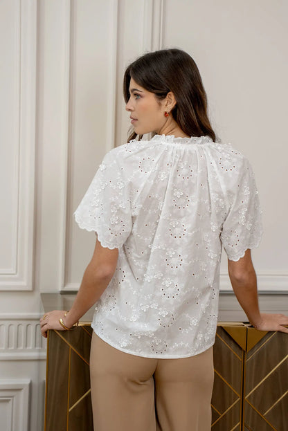 Mujer con camisa blanca manga corta bordada y pantalón beige, moda primavera casual.