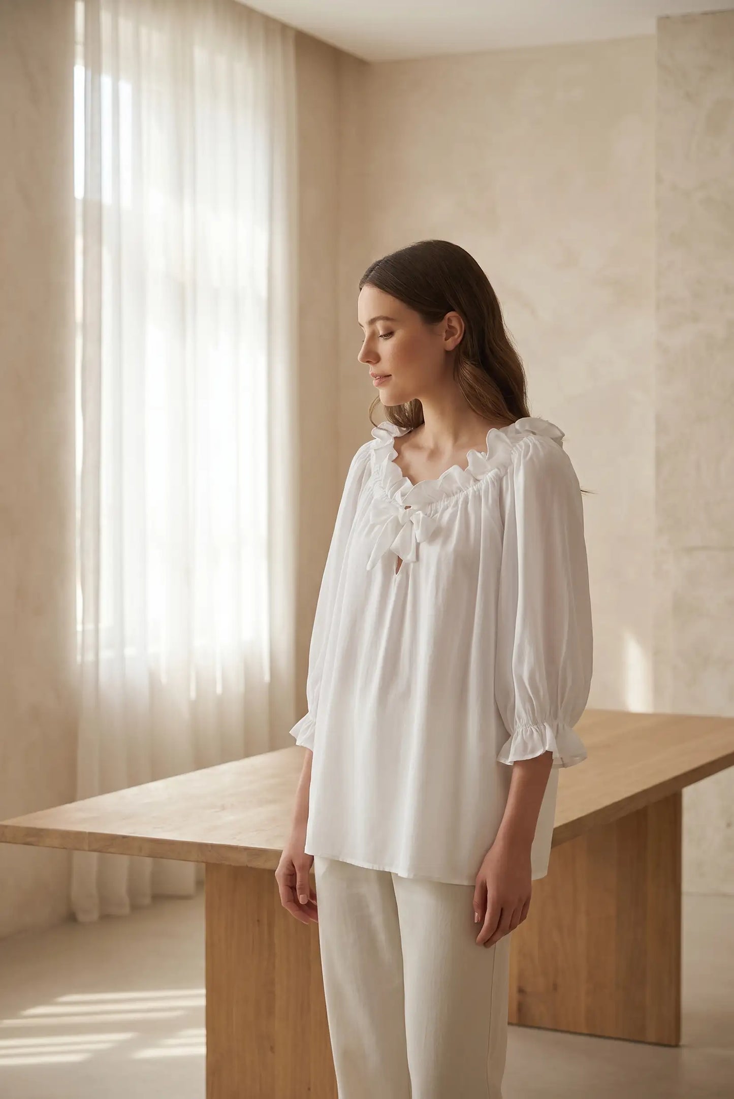 Mujer con blusa blanca manga francesa con volantes, look casual elegante, fondo interior luminoso