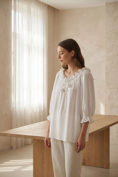 Mujer con blusa blanca manga francesa con volantes, look casual elegante, fondo interior luminoso