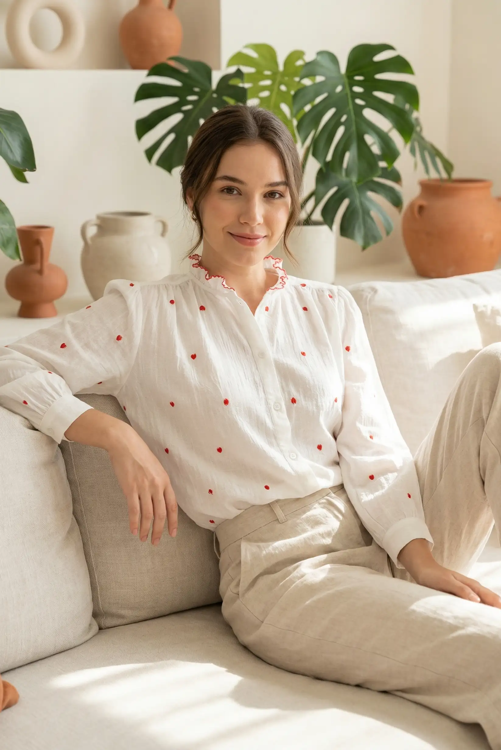 Mujer con camisa blanca de corazones rojos sentada en sofá, moda casual CHICA del Sur