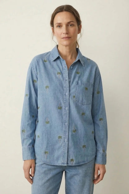 Mujer con camisa denim azul bordada con palmeras, look casual de primavera.
