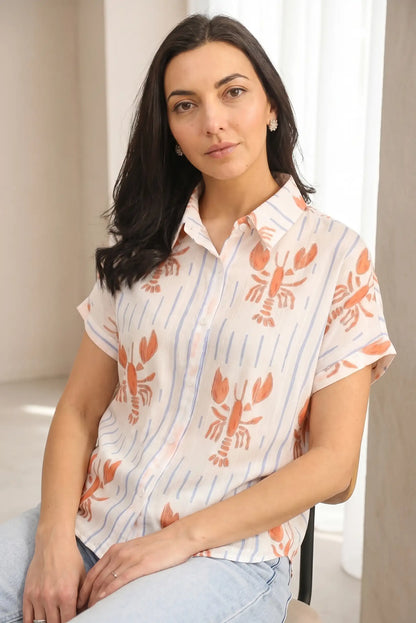 Mujer con camisa blanca de manga corta estampada con cangrejos, look casual primaveral