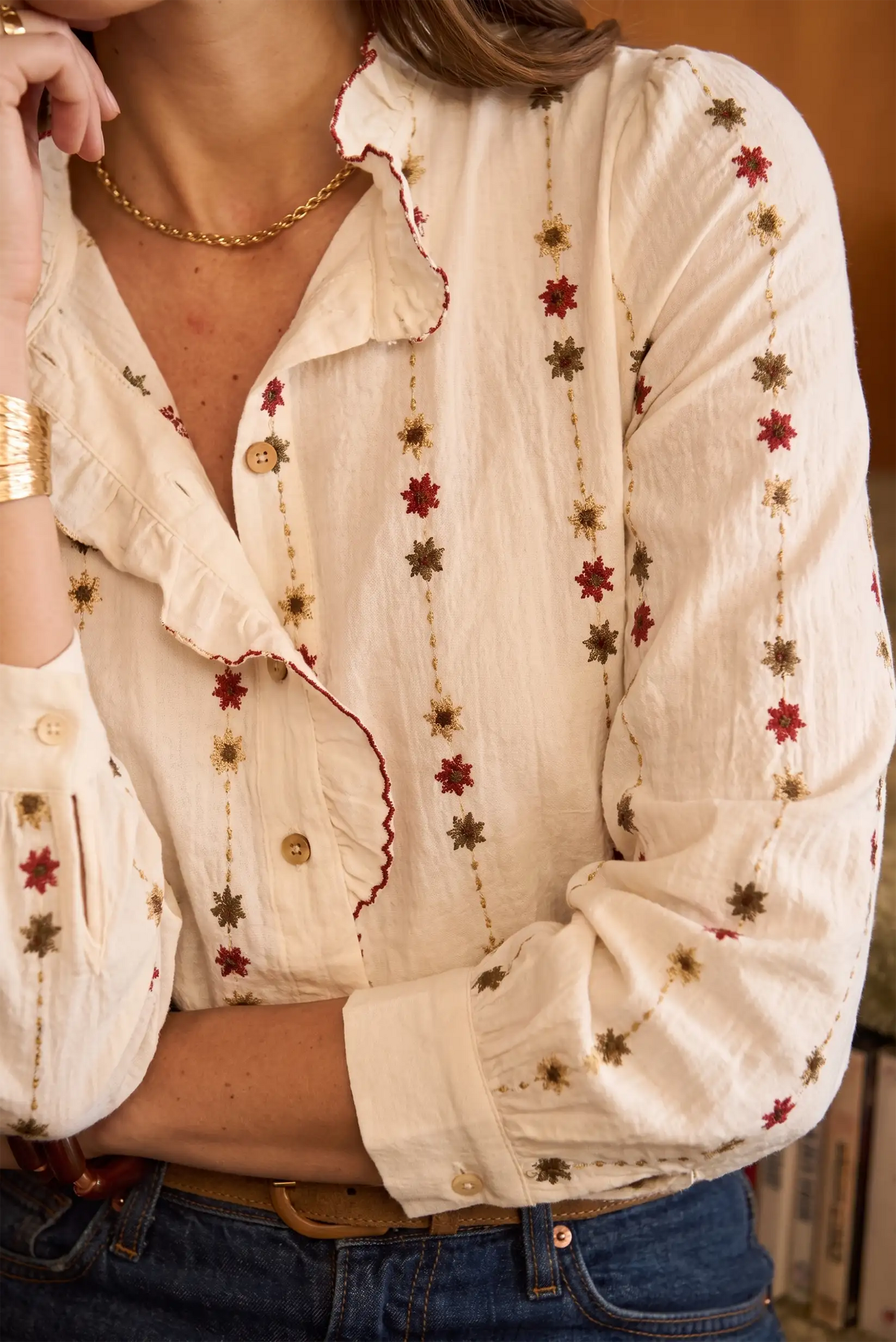 Blusa blanca con bordados florales rojos y dorados, cuello con volantes y botones